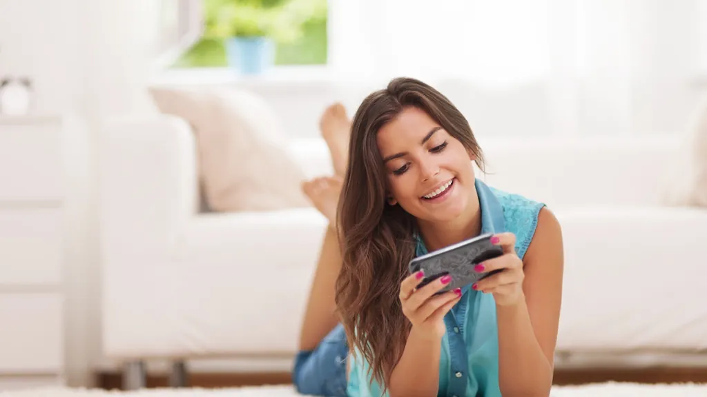 Person entspannt auf dem Sofa und schaut auf ihr Smartphone