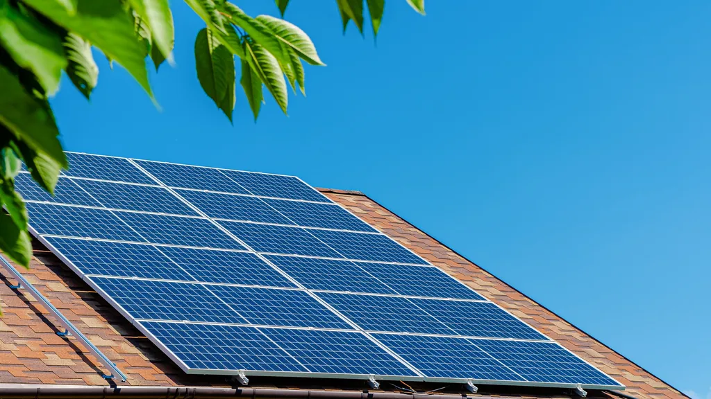 Solaranlage auf einem Dach unter klarem blauem Himmel, eingerahmt von Blättern